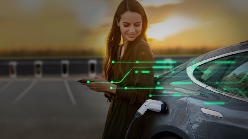 一位女士站在一辆正在充电的电动汽车 (EV) 旁边，此时她的手机已成功连接到车辆网络中。